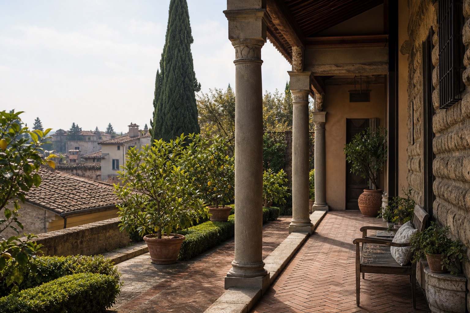 A Florentine loggia with stone columns, terracotta paving, citrus trees, and rooftops
